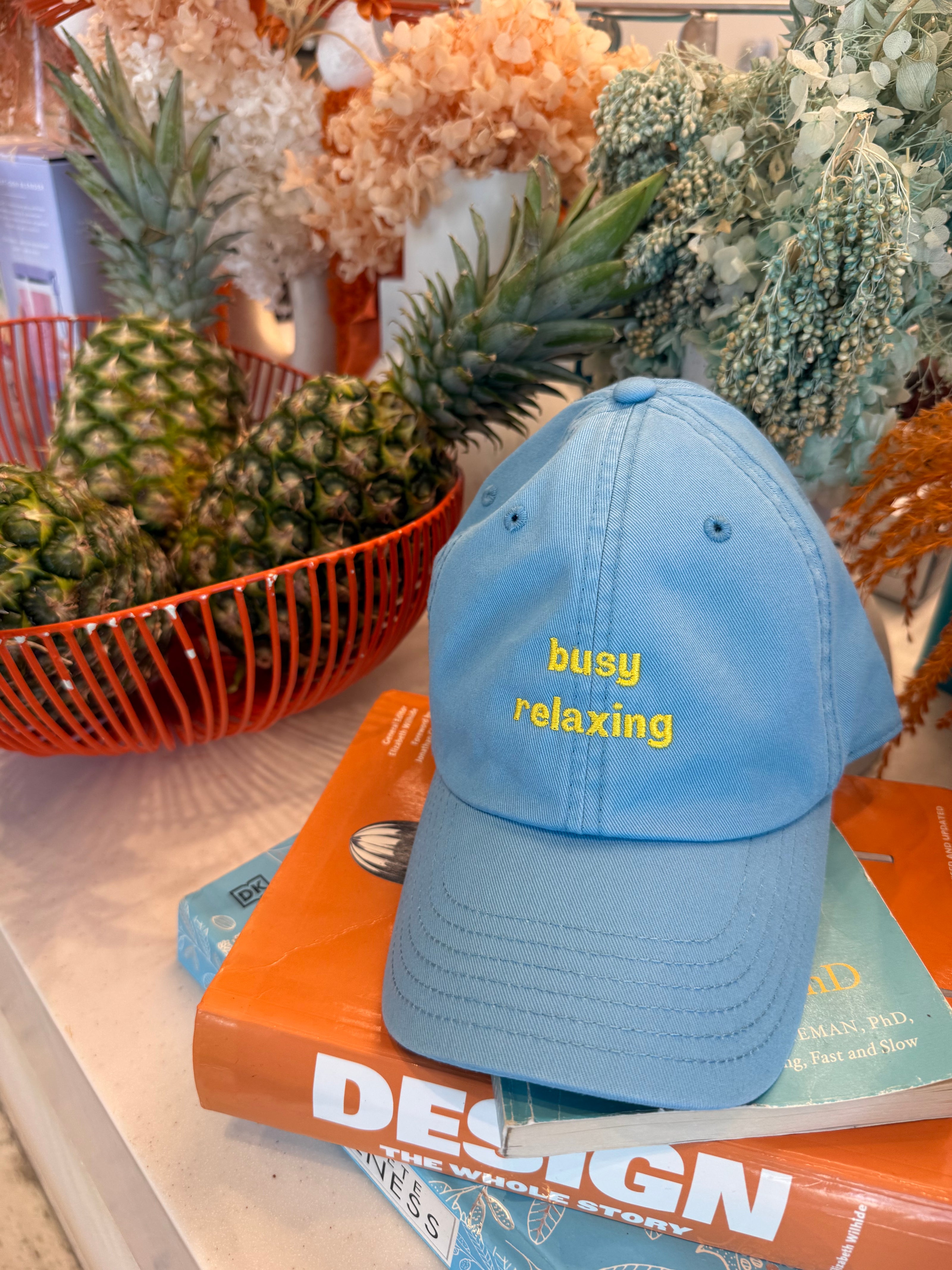 Blue cap with text on a surface with books and plants