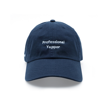 This image features a navy blue baseball cap with the phrase "Professional Yapper" embroidered in white on the front. The cap is designed with a classic style, featuring an adjustable strap with a buckle and metal hole for a snug fit.