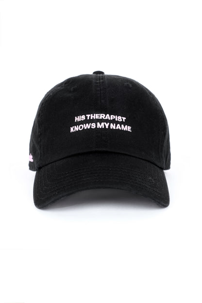 Black cap with embroidered text “His Therapist Knows My Name,” bold relationship-inspired cap.