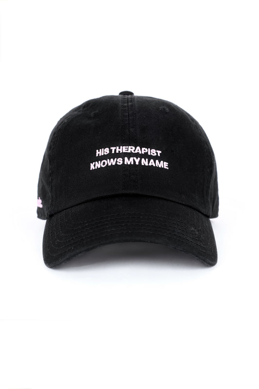 Black cap with embroidered text “His Therapist Knows My Name,” bold relationship-inspired cap.