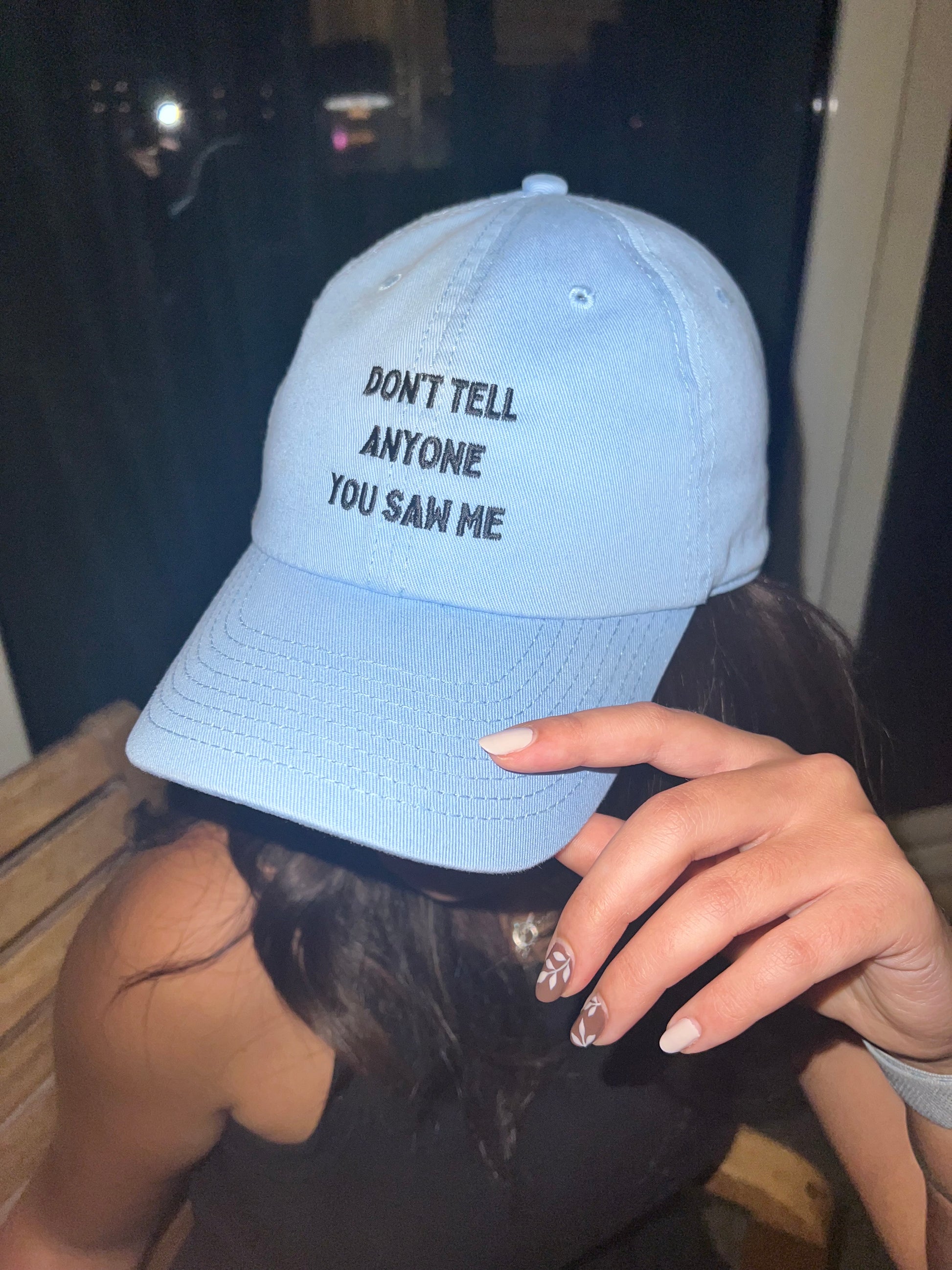 Light blue cap with text held by a person with dark hair and a blurred background